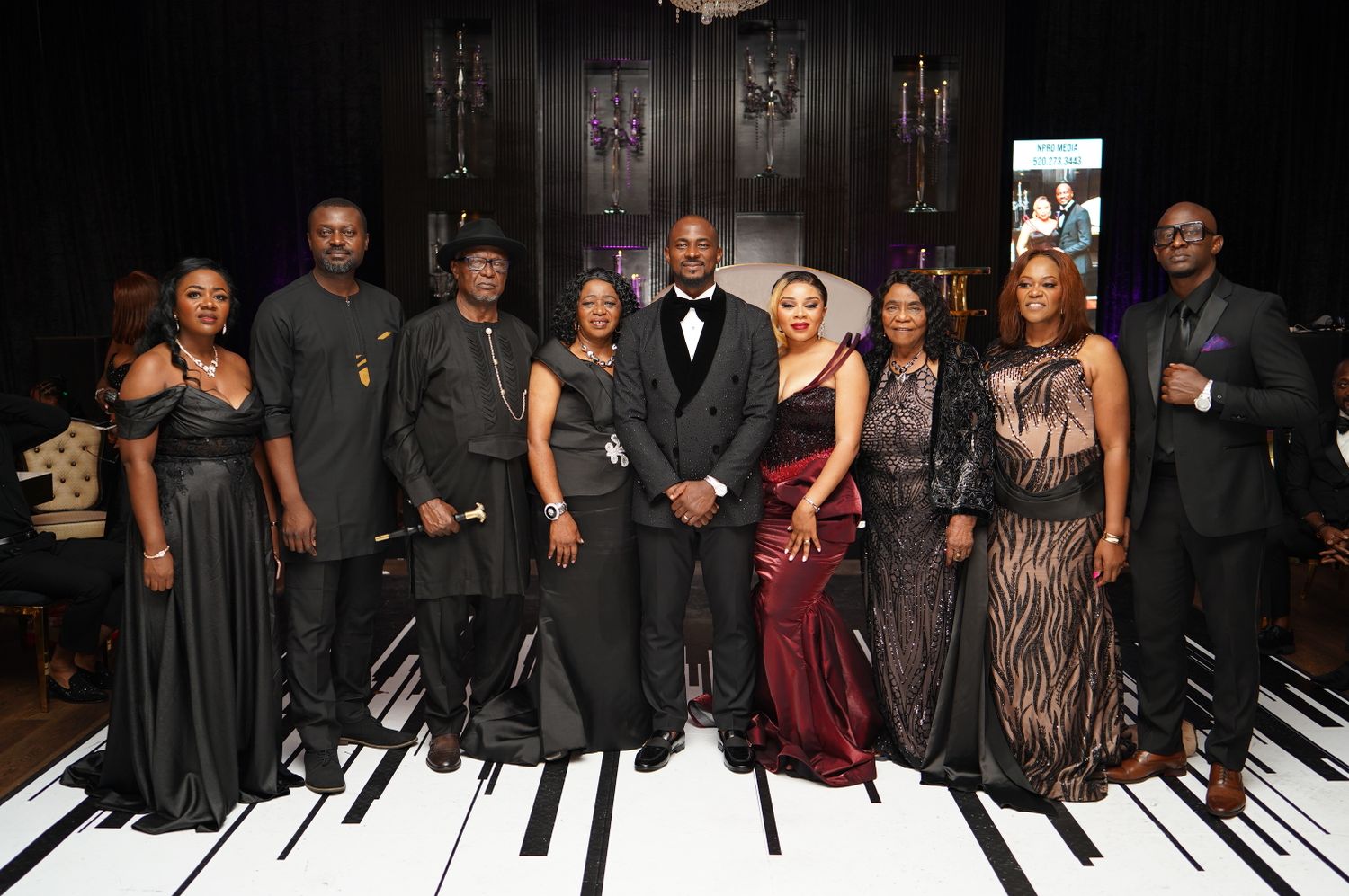 Guests in black tie at a Nigerian gala night beneath chandeliers