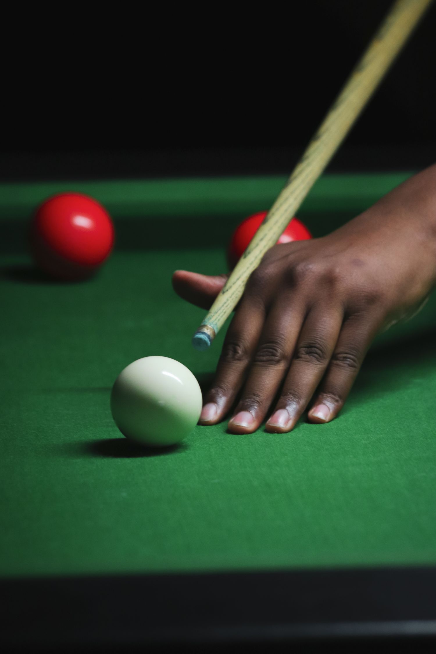 A player bridging a cue over the white ball on a green snooker table